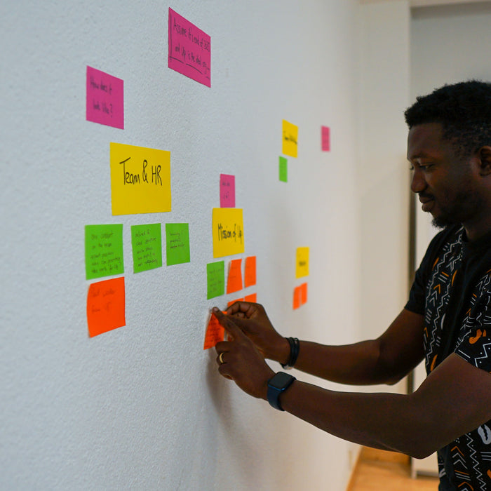 A workshop participant placing a note on a wall of clustered electrostatic notes